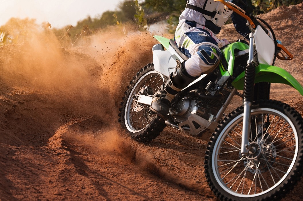 Young man practice riding dirt bike.Splashing sand