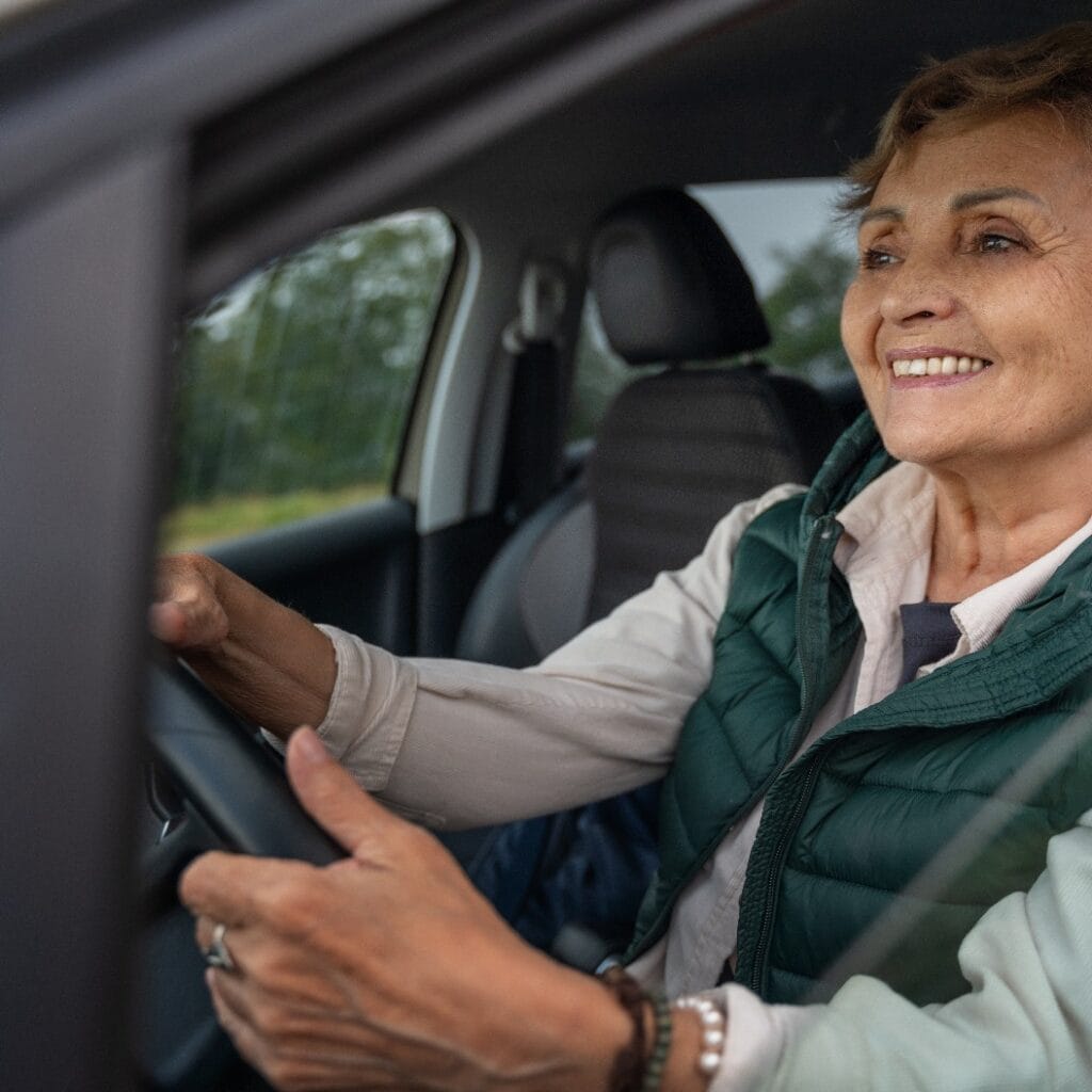 Beautiful happy smiling senior gray-haired mature woman driving a car